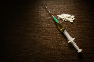 A needle and a pile of powder used in heroin addiction.