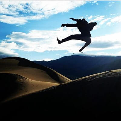 A sober young person jumping on the dunes in Denver, Colorado.
